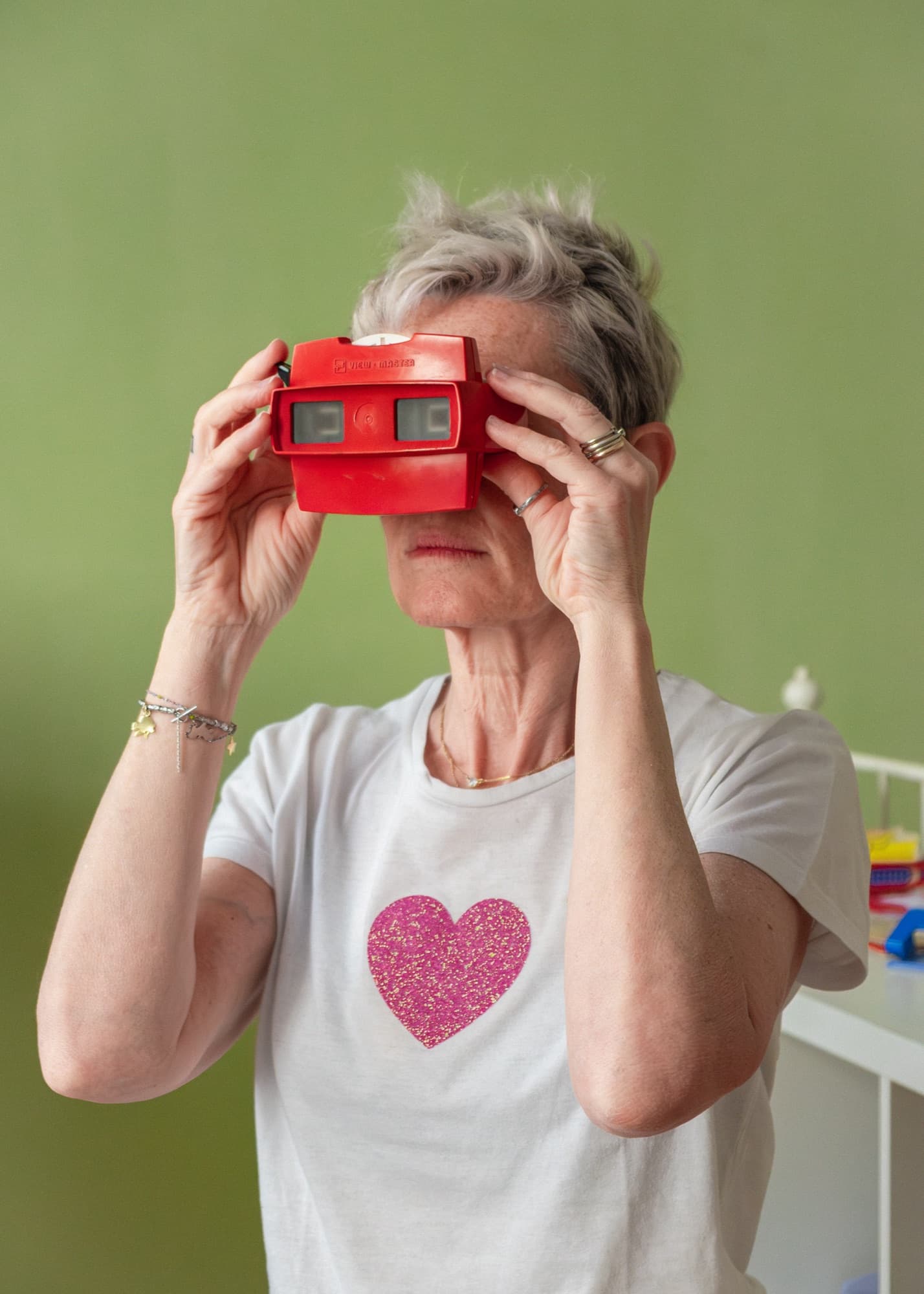 Una donna guarda dentro un View-Master rosso, davanti a un muro verde.